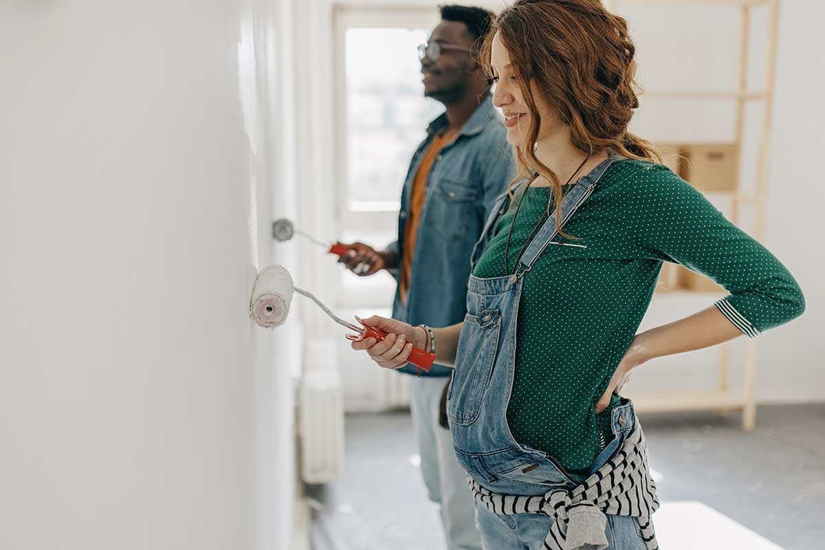 En gravid kvinna står med händerna på höfterna i ett hem, ser fokuserad ut.