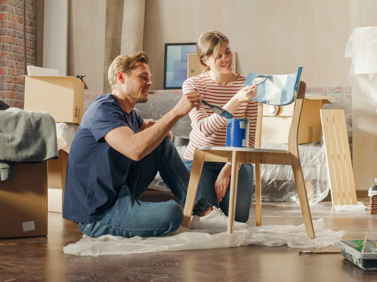 Ett par ler tillsammans i ett kök medan de håller i mobiltelefonen.