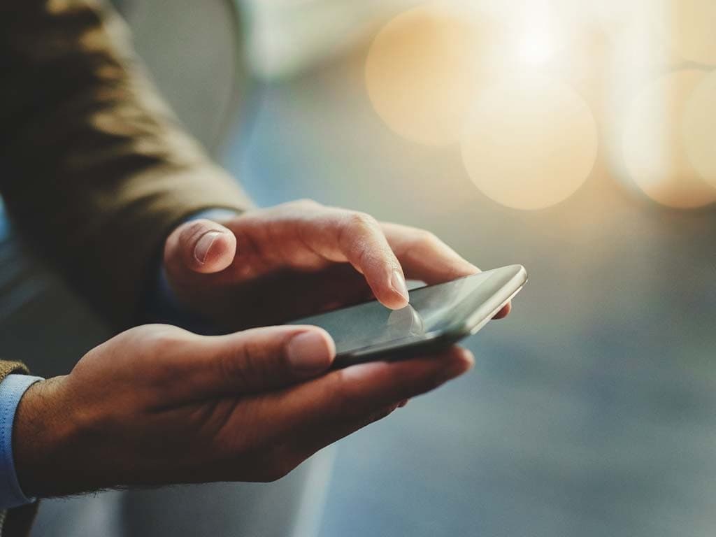 En person håller en smartphone i båda händer och bläddrar koncentrerat.